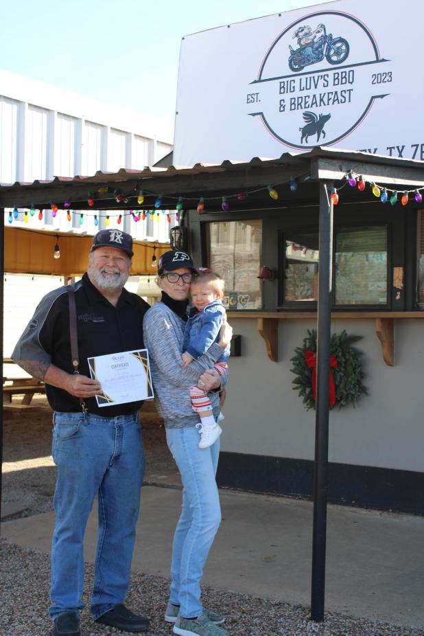 Barry and Ann Hodges and their grand-daughter Emilia Jane show off an Olney Chamber of Commerce certificate celebrating their second anniversary in business in Olney. Congratulations, Big Luv! Photo by Gina Keating