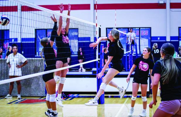 A varsity Ladycat slams a kill shot past a defender. Photo by Will Sadler