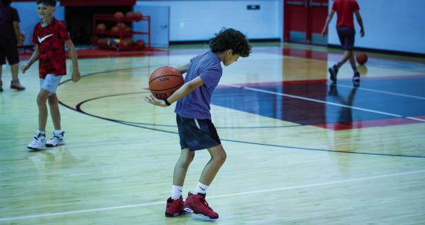 It wasn’t all work during the summer basketball camp; children played a game by tossing the ball into the air, clapping then attempting to catch the ball behind their backs. Photo by Will Sadler