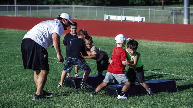 Football is a physical sport, and learning the basics, such as how to safely tackle and block, is important. These players look pretty serious but were all laughs after each player took their turn. Photo by Will Sadler