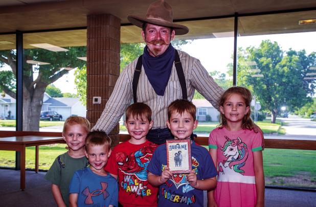 Cowboy Nick Waters, expert storyteller, poses with children who attended a session at the OCLAC after hearing a story about two young brothers, the Abernathy Boys. Photo by Will Sadler