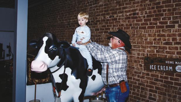 Precinct 4 County Commissioner Jimmy Wiley shows his grandson, Whip, how to ride a cow at the Olney Chamber Mix & Mingle event at the Olney Heritage Museum on Feb. 24. Whip is the son of Olney Chamber board member Tatum Wiley. Photo by Will Sadler