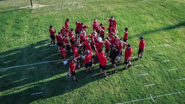 Cub players and coaches finish this year’s first practice with a huddle and a Cub shout before exiting the practice field to hit the weights; a Cubs preparation is never finished. Photo by Will Sadler