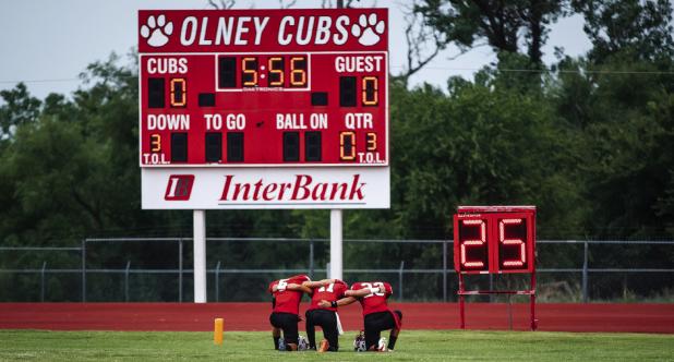 OHS Cubs [L-R] #5 Kanton Rodgers, #11 Tucker Cortinez and #3 Dom Collins take a knee taking a moment in prayer before their game against Petrolia. Photo by Will Sadler