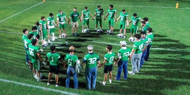 The Newcastle athletes form up into a circle ahead of their Homecoming game against Guthrie to share fellowship, prayer, and words of encouragement.
