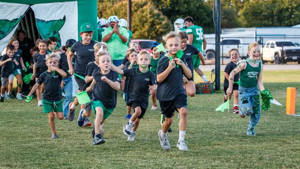 The Newcastle Pounce lead the way for their older counterparts before the NHS Bobcat HOCO game begins. The Pounce are made up of K-fifth graders who receive a shirt during pre-season, and each game receive a water and hot dog and lead the charge coming ou