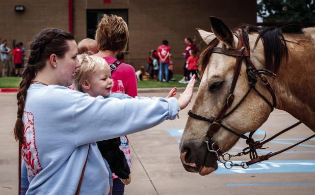The Stewart family arrived on horseback and the children just fell in love with the horses from the start. The children offered warm smiles, cute giggles and tiny hands to pet the horses’ soft snouts. Photo by Will Sadler