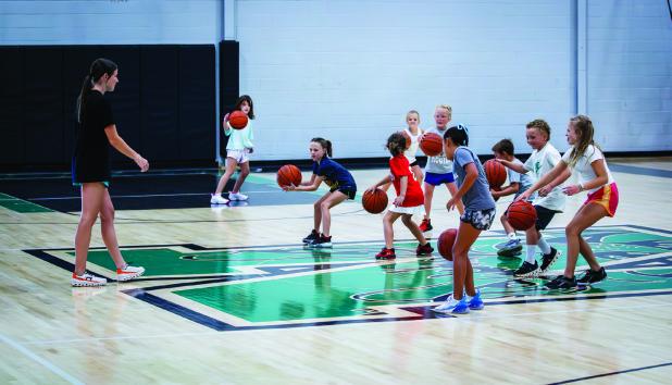The children attending the summer basketball camp had fun competing against each other in dribbling drills. Photo by Will Sadler
