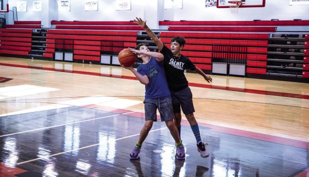Two Cubs practice offense and defense under the basket. During camp, there are many ways to earn prizes, but the best is bragging rights over friends and fellow camp attendees. Photo by Will Sadler