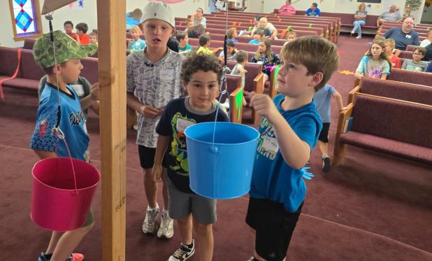 Children at Southside Baptist’s vacation bible school bring offerings for Operation Christmas Shoebox. Photo by Candy Blair
