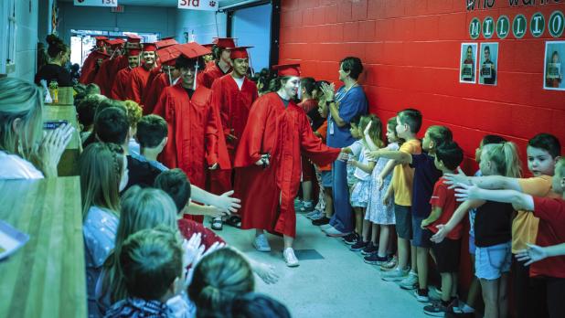 OHS graduates participate in a much-beloved time-honored tradition of walking through the halls of Olney Elementary School wearing caps and gowns and greeting waiting students’ high fives and huge smiles. Photo by Will Sadler