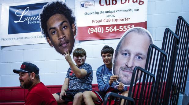 Cub fans supporting Varsity Cub Shareginald Williams [L] and Coach Eric Symank [R], excitedly holding up giant heads of their heroes for the night. Photo by Will Sadler