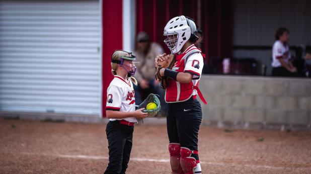 Lady Cubs pitcher and catcher have an impromptu meeting during the first game. Photo by Will Sadler