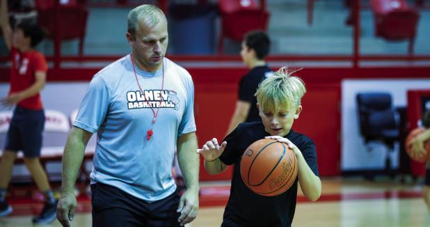 Coach Symank is teaching a large group of children basketball skills over the summer, which includes one on one coaching time. Kids also learn teamwork, passing, dribbling, shooting and good sportsmanship along with many other useful skills. Photo by Will