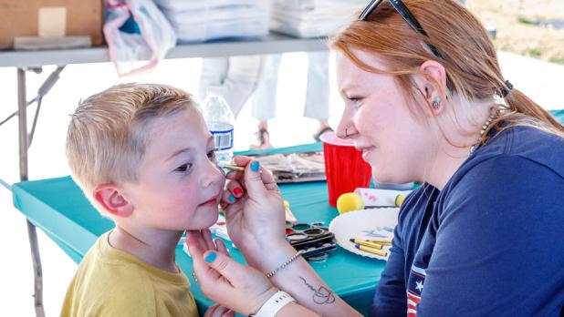 OPD Chief Bryan Barrett’s daughter Katy Barrett donated her time and artistic skills to face paint the children at the Olney National Night Out. Photo by Will Sadler