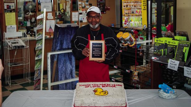 Don Atkinson receives a plaque from Stewart’s Food Store for 20 years of service at the family-owned grocery store at a special celebration last week. Photo by Will Sadler