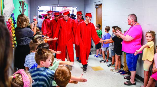 Olney High School Seniors take a traditional stroll down Olney Elementary School’s Hall in cap & gown before graduating. The children really enjoy the high fives and hugs. Photo by Will Sadler