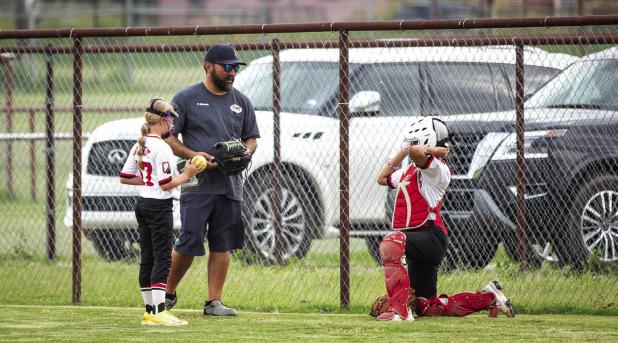 A Lady Cubs coach gives last-minute instructions to the pitcher and catcher before the game begins against the Lady Heat. Photo by Will Sadler
