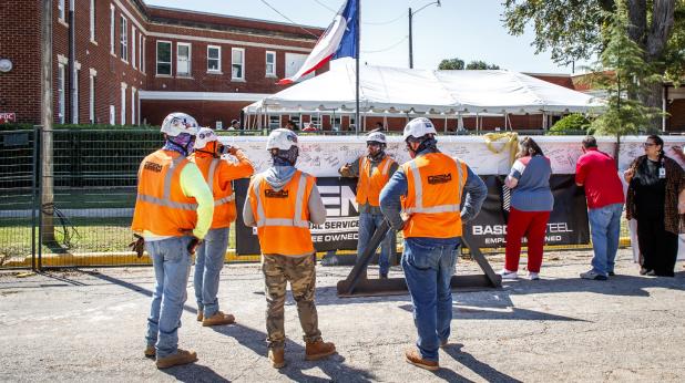 Construction crews wait as attendees at the topping off ceremony for the new Olney Hamilton Hospital sign their names to the final beam to be hung for the new building. Photo by Will Sadler