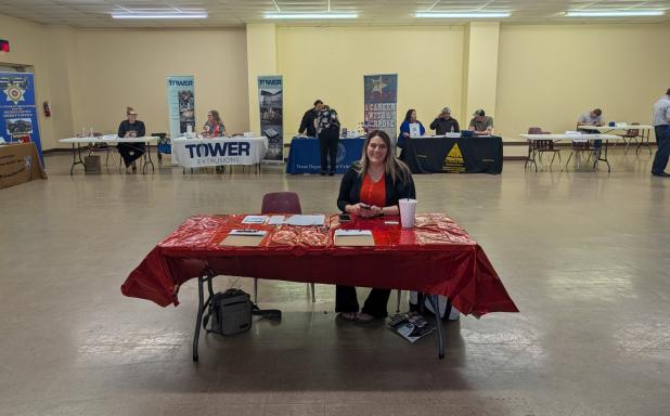 Olney Chamber of Commerce director Kimberly Smith sits at the welcome table at the first Olney Job Fair, sponsored by the Chamber and Texas Workforce Solutions. Behind her are (l-R): Avir in Olney, Tower Extrusions, Texas Dept of Criminal Justice, Air Tra