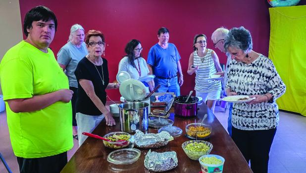 Attendees of the Cub Center June Game Night line up to fill their plates with delicious treats while chatting with each other about happenings around town. Photo by Will Sadler