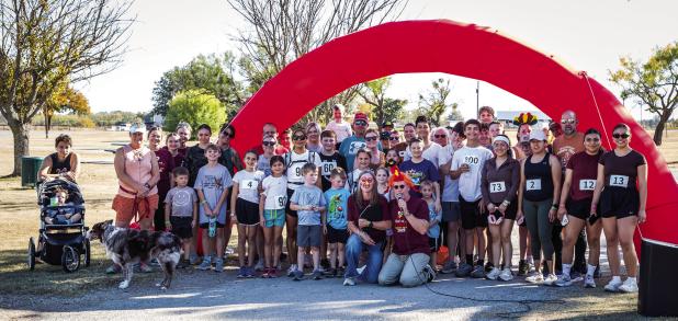 Shown are the participants and volunteers of the Sixth Annual Turkey Trot at Tom Griffin Park on Sunday, Nov. 16. Participants warmed up with a prayer and a chicken Photo by Will Sadler