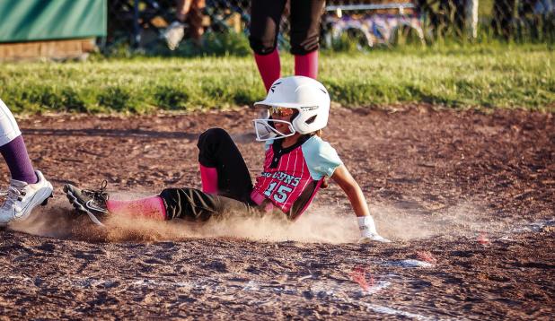 A Young Gun slides into home plate scoring a point to help add to the win for the day; she was all smiles. Photo by Will Sadler