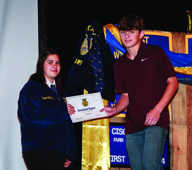 OHS FFA Reporter Valerie Hance presents FFA member Will Caffey with the Green Hand Degree. The Green Hand Degree is generally the first degree a new FFA member will earn after joining the FFA, signifying they have a good understanding of the history and p
