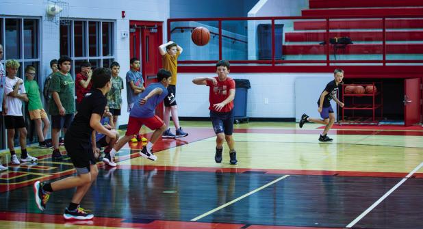 Attendees of the basketball camp practice passing as they race back and forth on the court passing the ball as they go. Photo by Will Sadler