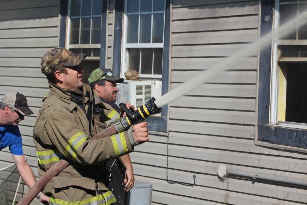 Olney Firefighter Jason Pack mans a hose during a house fire near the Young County/Archer County border.
