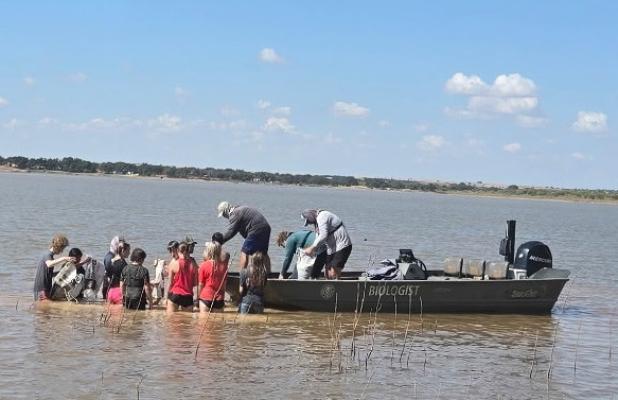 OHS freshmen and sophomore science students assist Texas Parks and Wildlife biologist Wes Dutter in building three additional fish spawning beds at Lake Cooper last month. The group followed junior and senior science students who built three beds for the