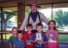 Cowboy Nick Waters, expert storyteller, poses with children who attended a session at the OCLAC after hearing a story about two young brothers, the Abernathy Boys. Photo by Will Sadler