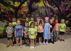 The First Baptist Church of Olney’s kindergarten class stands in front of a huge magnifying glass at their Vacation Bible School music class. Photo by FBCO